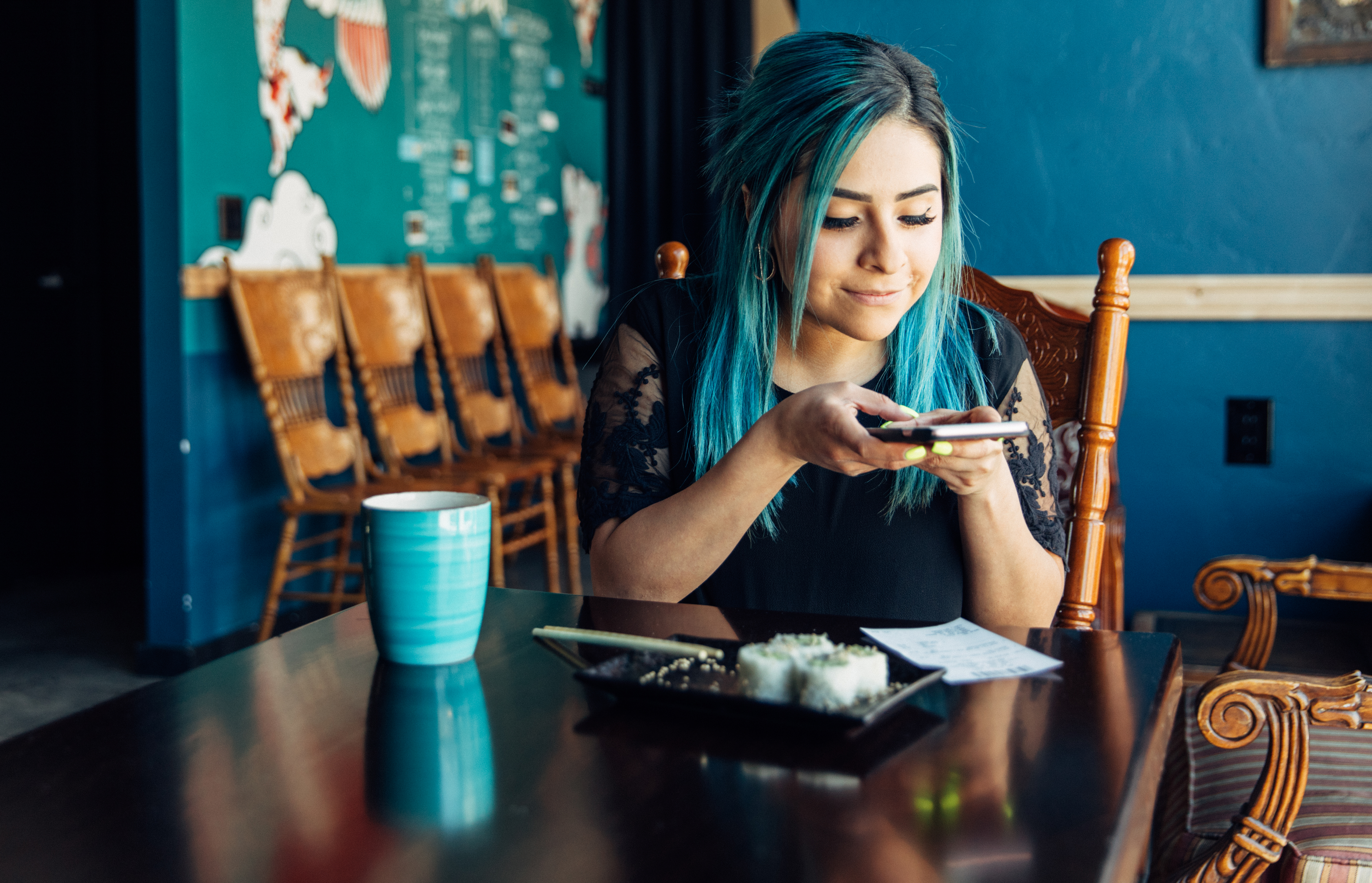 Woman of the Millennial Generation are taking a picture of a restaurant receipt after eating lunch at a local sushi restaurant.