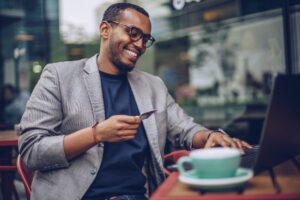 Attractive young man sitting in coffee shop and using laptop computer