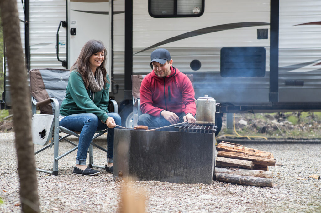 Young couple at bonfire with camper